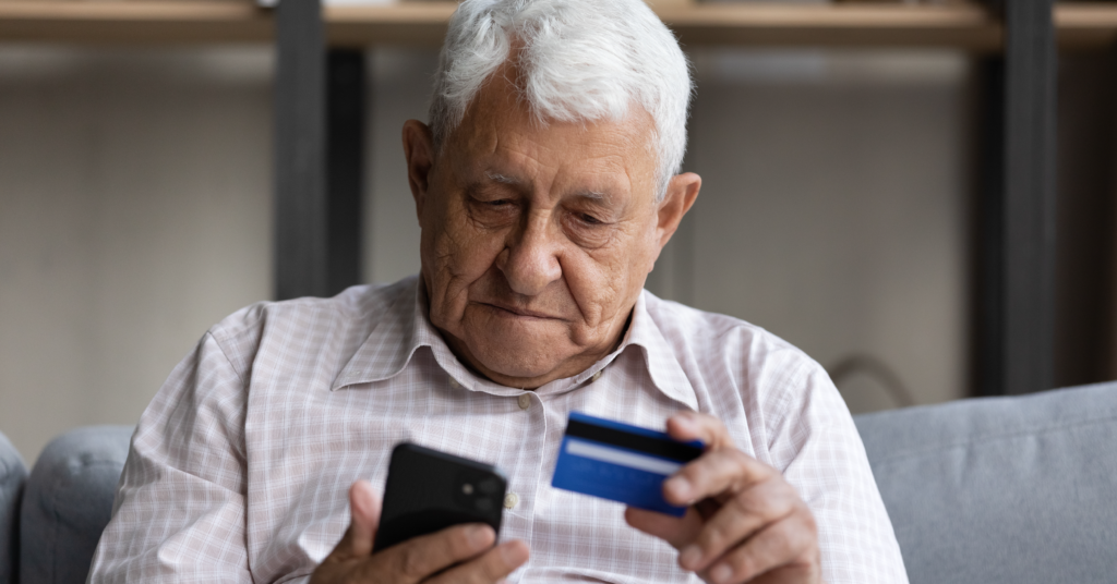 Older man holding cell phone and debit card