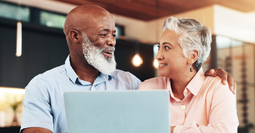 Elderly couple sits at a laptop together