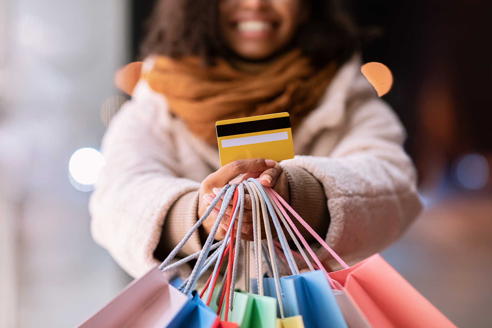 Smiling woman holding her debit card along with her shopping bags